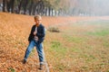 Smiling stylish young boy outdoors in autumn. Kid having fun in autumn city park among fallen leaves. Street urban fashion style Royalty Free Stock Photo