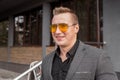 Smiling stylish young guy businessman of European appearance in a gray jacket and black shirt portrait in glasses on the street Royalty Free Stock Photo