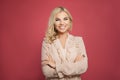 Smiling successful woman on colorful pink background. Blonde girl with crossed arms and pretty smile