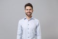 Smiling successful young unshaven business man in light shirt posing isolated on grey wall background studio portrait Royalty Free Stock Photo