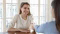 Smiling successful young woman candidate shaking recruiter employer hand