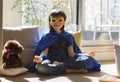 Smiling superhero child with mask enjoying happy yoga, fun meditation