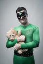 Smiling superhero cuddling a teddy bear Royalty Free Stock Photo