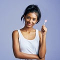 Smiling sweetly. Studio portrait of a beautiful young woman sucking on a lollipop against a purple background. Royalty Free Stock Photo