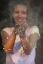 Smiling tanned asian woman covered with Holi paint posing with g