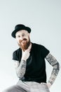 smiling tattooed man touching beard and looking at camera