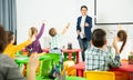 Smiling teacher examining pupils at lesson