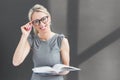 Smiling teacher with glasses standing in front of blackboard and holding book Royalty Free Stock Photo