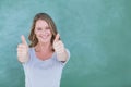 Smiling teacher standing thumbs up in front of blackboard