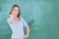 Smiling teacher standing thumbs up in front of blackboard Royalty Free Stock Photo