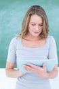 Smiling teacher using tablet pc in front of blackboard Royalty Free Stock Photo