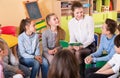 Smiling teacher woman reading to children during lesson in schoolroom Royalty Free Stock Photo