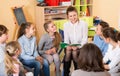 Smiling teacher woman reading to children during lesson in schoolroom Royalty Free Stock Photo
