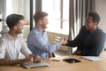 Smiling team leader handshaking with black client