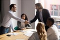 Smiling team leader shaking successful employee hand at corporate meeting