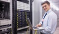 Smiling technician using laptop while analysing server