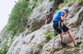 Smiling teen boy in protective helmet abseiling from cliff rock wall using rope, Belay device and climbing harness with father in Royalty Free Stock Photo