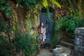 Smiling teen girl in dress with dachshund dog against old metal door with colorful creeper plants around