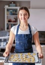 Smiling teen girl holding baking tray with homemade cookies  at home looking at camera. Royalty Free Stock Photo