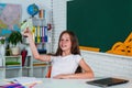 smiling teen girl play with paper plane in school classroom, childhood