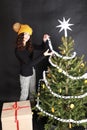 Smiling teen girl putting white paper chain on Christmas tree