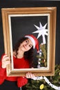 Smiling teen girl in red Christmas cap behind old frame