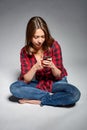 Smiling teen girl sitting barefooted at floor smiling at camera