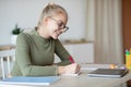 Smiling teen girl studying at home and using laptop Royalty Free Stock Photo