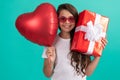 smiling teen girl in sunglasses hold gift box and valentines party heart balloon, happy childhood.