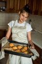 Smiling teen girl taking cookies out of the oven in the kitchen.Homemade cakes, cookies and gingerbread cookies. sweet breakfast Royalty Free Stock Photo