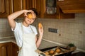 Smiling teen girl taking cookies out of the oven in the kitchen.Homemade cakes, cookies and gingerbread cookies. sweet breakfast Royalty Free Stock Photo