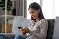 Smiling girl using mobile social media app sitting on couch Royalty Free Stock Photo