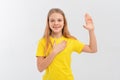 Smiling teen girl wearing casual yellow t shirt, swearing with hand on chest and open palm, making a loyalty promise oath, Royalty Free Stock Photo