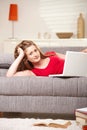 Smiling teen with laptop on sofa at home Royalty Free Stock Photo