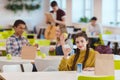 smiling teen schoolgirl sitting at school cafeteria with classmates and looking