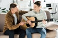 Smiling teen son playing acoustic guitar for father Royalty Free Stock Photo