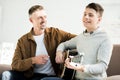 Smiling teen son playing acoustic guitar for father Royalty Free Stock Photo