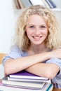 Smiling teen studying a lot of books