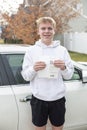 Smiling teenage boy holding his driving learners permit document