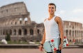 Smiling teenage boy with skateboard over coliseum Royalty Free Stock Photo