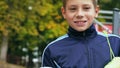 Smiling teenage boy with a soccer ball in his hand and soccer boots on the shoulder against the background of the Royalty Free Stock Photo