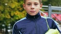 Smiling teenage boy with a soccer ball in his hand and soccer boots on the shoulder against the background of the Royalty Free Stock Photo