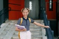 A smiling teenage girl with a backpack and a folder in her hands goes down the stairs, hurries to school. Back to school Royalty Free Stock Photo