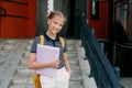 A smiling teenage girl with a backpack and a folder in her hands goes down the stairs, hurries to school. Back to school Royalty Free Stock Photo