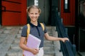A smiling teenage girl with a backpack and a folder in her hands goes down the stairs, hurries to school. Back to school Royalty Free Stock Photo