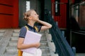 A smiling teenage girl with a backpack and a folder in her hands goes down the stairs, hurries to school. Back to school Royalty Free Stock Photo