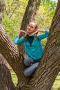Smiling teenage girl climbed a tree in the park