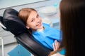 Smiling teenage girl communicates with female hygienist in dental office