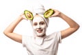 Smiling teenage girl cosmetics mask skin beauty. Teenage girl doing anti blemish skin treatment holding avocado fruit Royalty Free Stock Photo