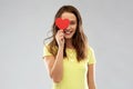 Smiling teenage girl covering her eye by red heart Royalty Free Stock Photo